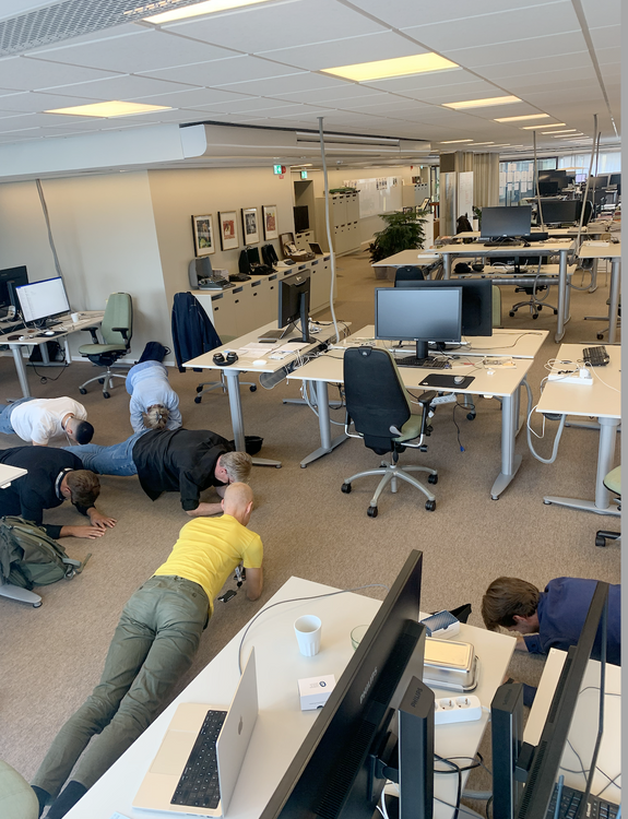 Kontorslandskap med 6 människor som står i plankan på golvet